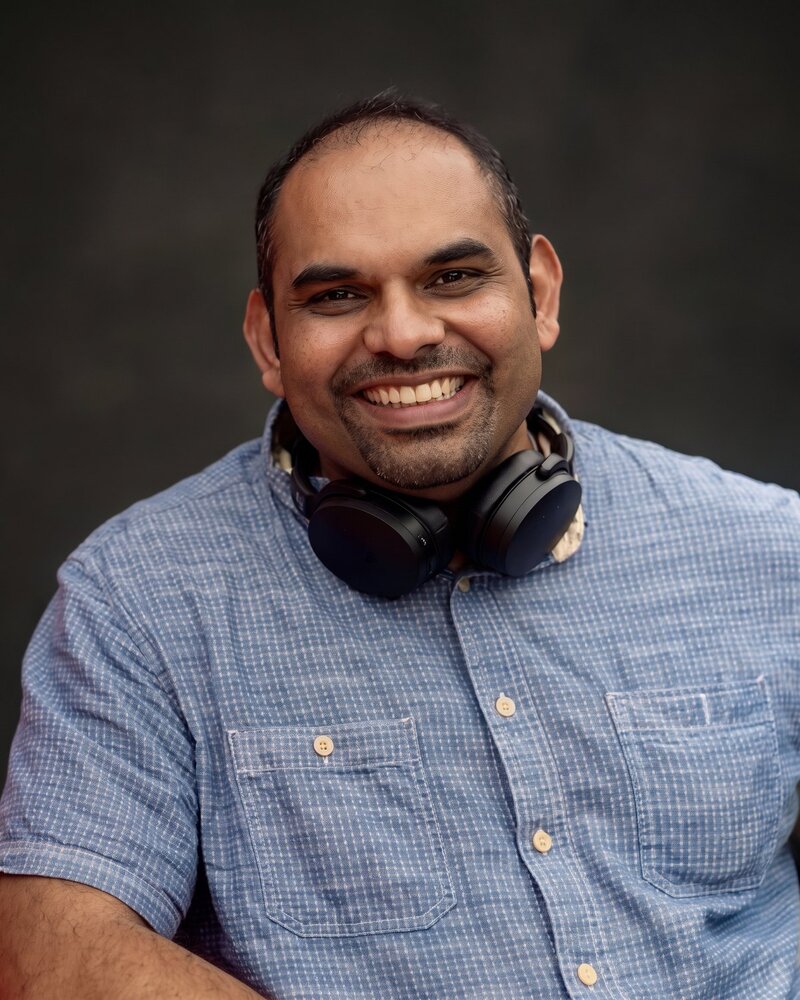 Dr Menon laughing, headphones around his neck